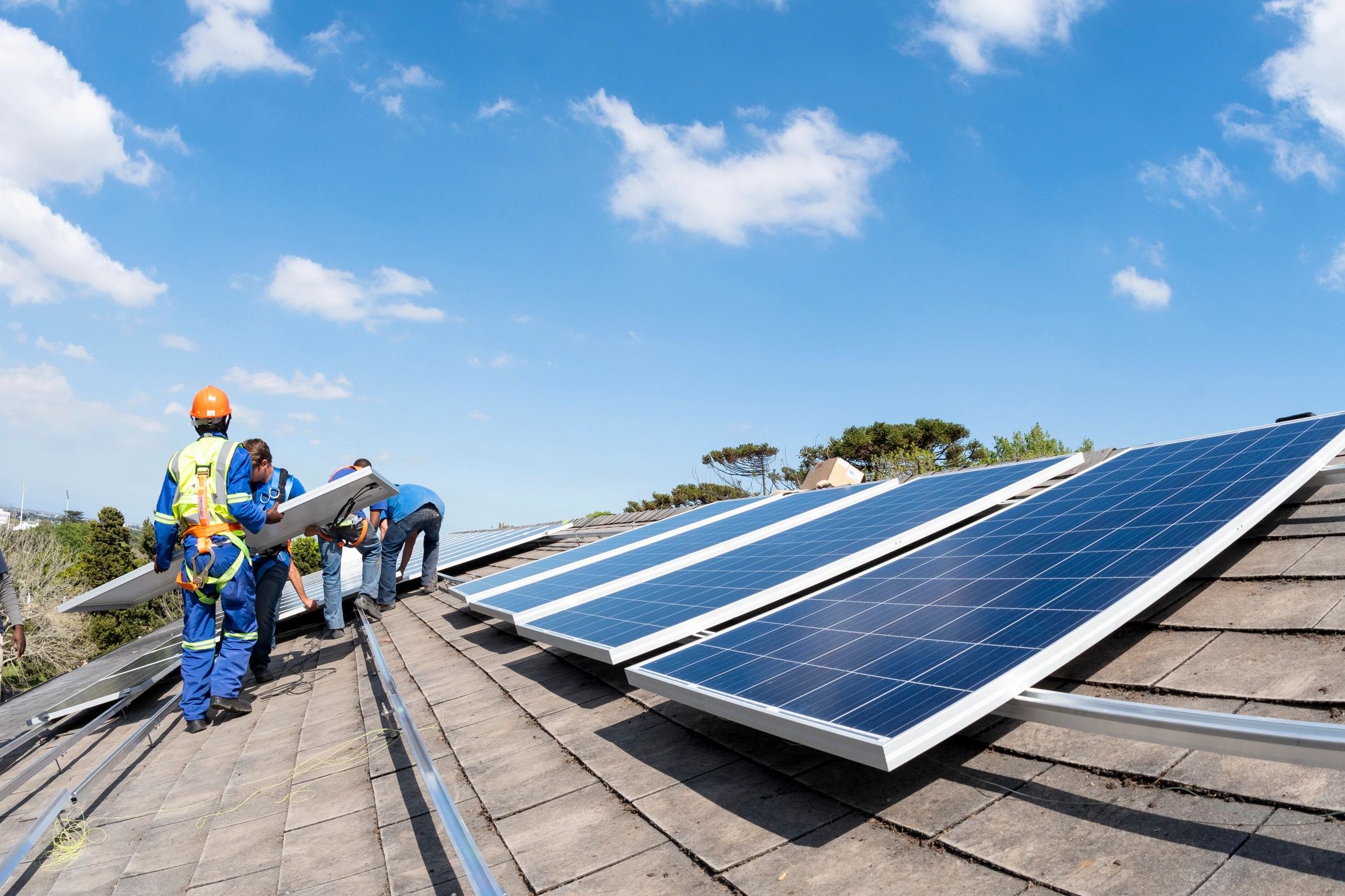 Workers installing solar panels on a roof
