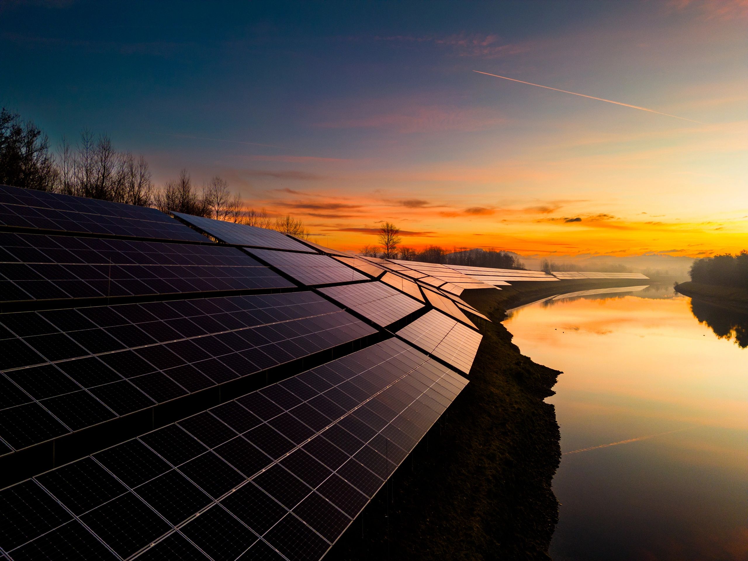 Solar power station by river during sunset